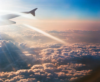 Cropped image of airplane wing over cloudscape