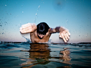 Man diving in lake against blue sky during sunset