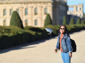 Portrait of smiling woman standing against buildings