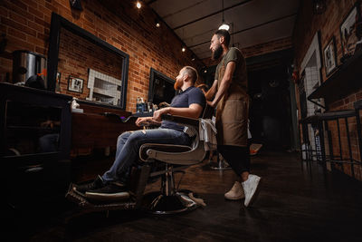 Side view of barber with male customer in salon