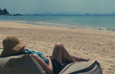 Young woman lying on bean bag at beach to take sunbath on summer vacation
