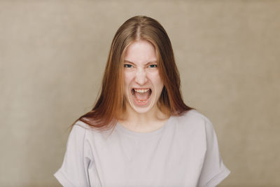 Portrait of young woman standing against wall