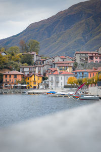 Houses by river and buildings against sky