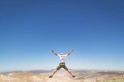 Rear view full length of man jumping against landscape