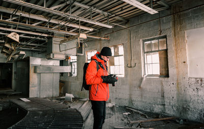 Side view of young man photographing in abandoned factory