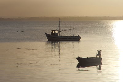 Boat moored on sea against sky during sunset