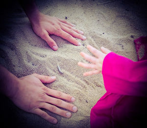 High angle view of woman hands on sand