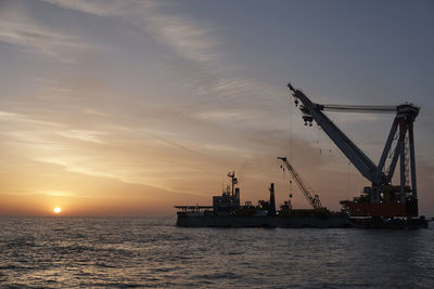 Silhouette ship by sea against sky during sunset