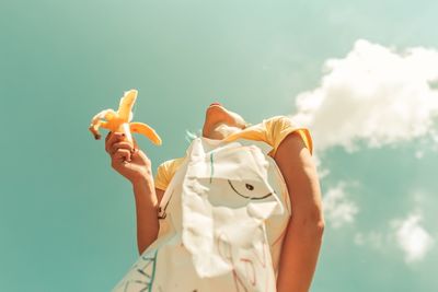 Low angle view of woman holding camera against sky