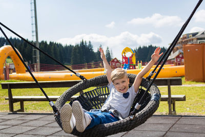 Portrait of happy boy swinging in playground