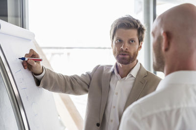 Two businessmen having a discussion at flipchart in office