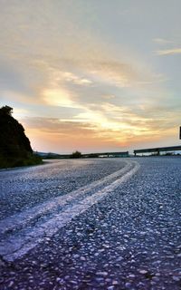 Surface level of road against sky during sunset