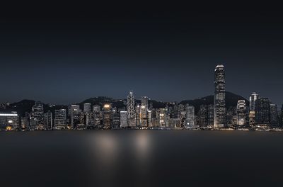 Illuminated modern buildings against clear sky at night