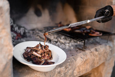 Unrecognizable man collecting the meat from the barbecue using tongs . close up.