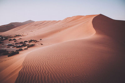 Sand dunes in desert against clear sky