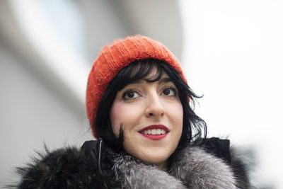 Young woman with red cap in winter in front of modern buildings