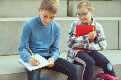 Full length of a boy sitting on book