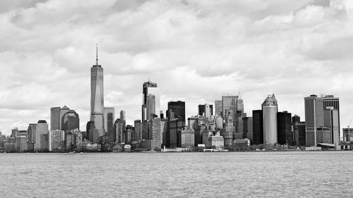 City at waterfront against cloudy sky