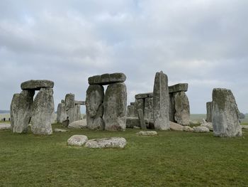 Stone structure on field against cloudy sky