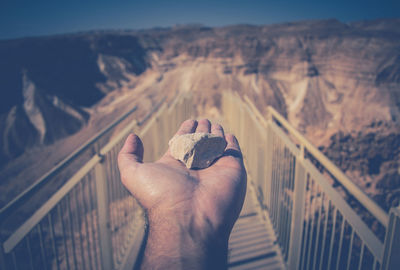 Cropped image of man holding stone amidst railings