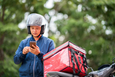 Delivery boy checking directions while holding mobile phone on street