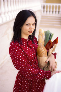 Portrait of young woman with eyes closed standing against wall