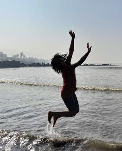 A girl jumping joyfully over the sea water in maharashtra in india