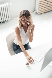 Smiling businesswoman talking on mobile phone sitting at desk