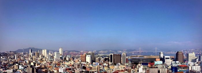 Panoramic view of crowd in city against clear blue sky