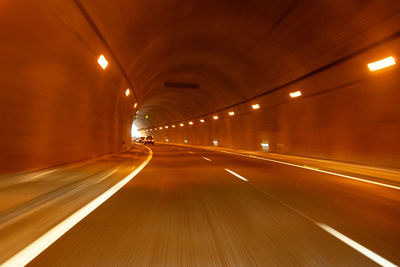 Illuminated light trails on road in tunnel