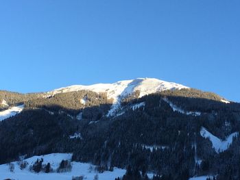 Scenic view of snow covered mountains against clear blue sky