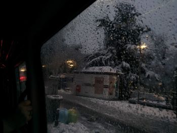 Illuminated street seen through wet window during rainy season at night