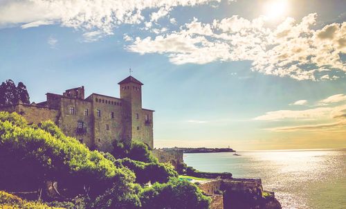 Buildings by sea against sky