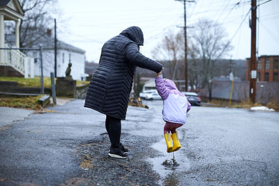 A mother and child having fun jumping in puddles.