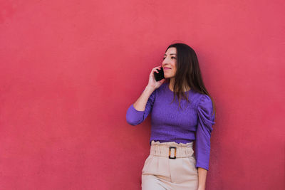 Full length of woman standing against pink wall