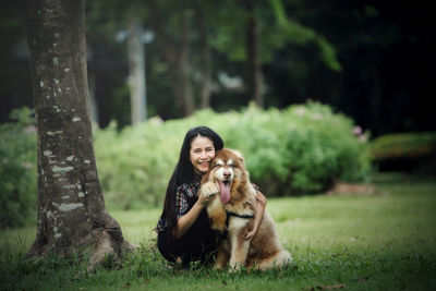 Woman with dog sitting on land