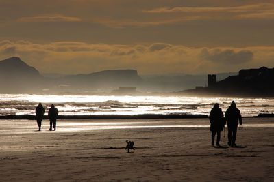 Silhouette people on beach against sky