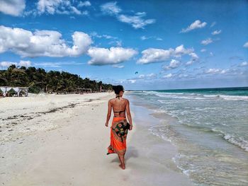 Solo traveller walking along the beach in mexico. blue sea, white waves, paradise beach.