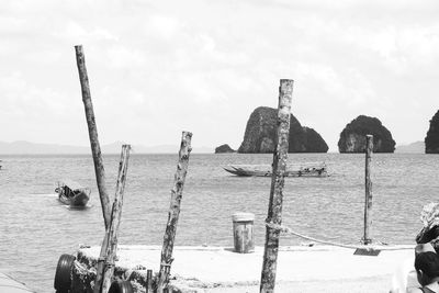 Wooden posts on beach against sky