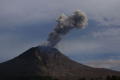 Smoke emitting from volcanic mountain against sky