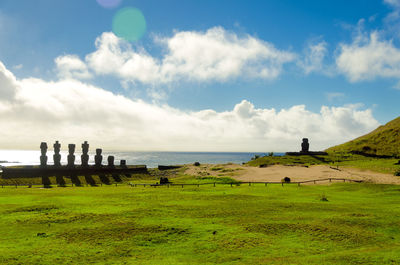 Moai statues at beach against sky