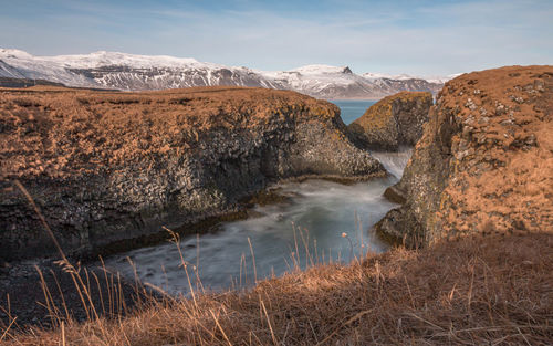 Full frame view of panoramic scenery of volcanic coastline with snow capped mountains in background