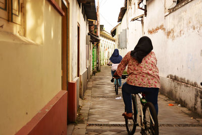 Rear view of women walking on alley in city