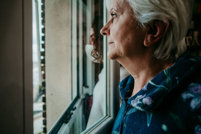 Portrait of woman looking through window