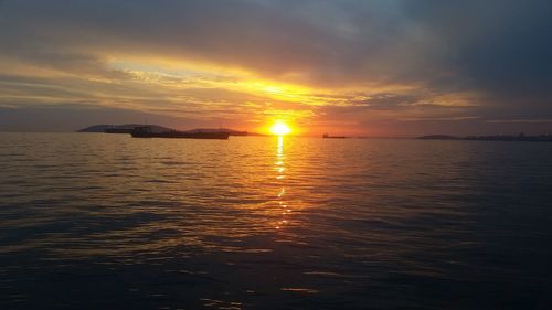 Scenic view of sea against dramatic sky during sunset