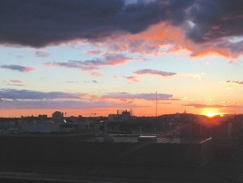 Silhouette of train against cloudy sky at sunset