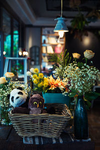 Soft toys in basket and flower pots arranged on table at cafe