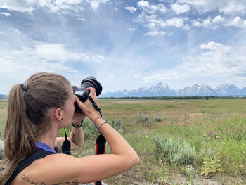 Full length of woman photographing against sky