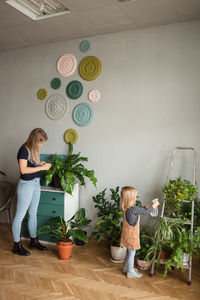 Woman and child care about green plants at cozy modern apartment.