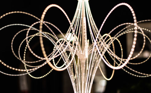 Low angle view of illuminated lighting equipment against black background